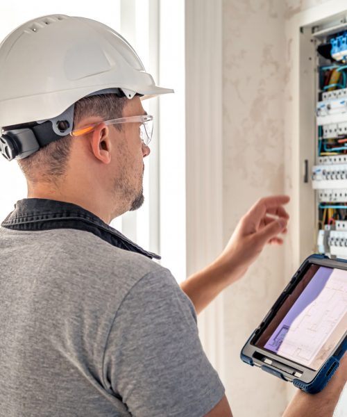 Man, an electrical technician working in a switchboard with fuses. Installation and connection of electrical equipment.